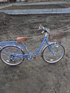 なかば鍼灸院の通勤用として迎えた青い子ども用自転車。旧院の跡地（更地）にて撮影。